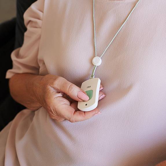 Woman pressing an emergency call button hanging around a lanyard on her neck
